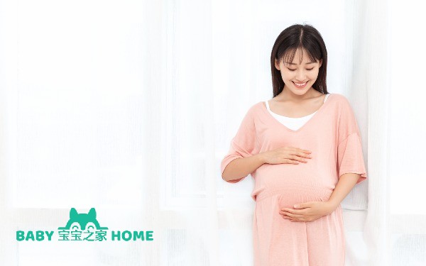 摄图网_501369097_一个孕妇在客厅站着抚摸肚子（企业商用）.jpg